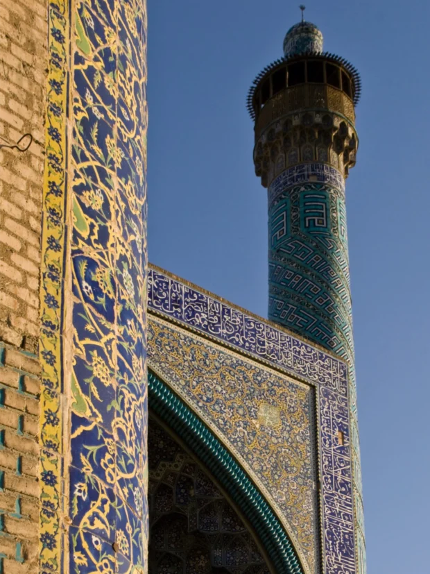 Minaret and tiled spandrel against flat blue.