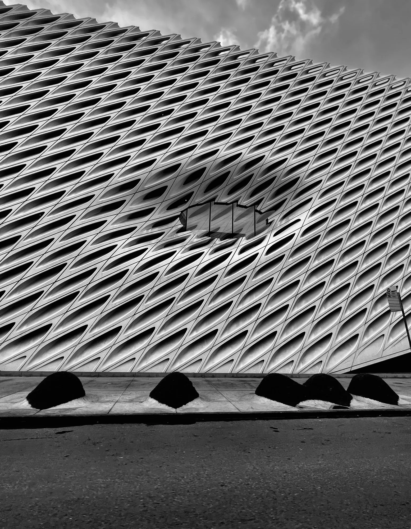 The diagonal lattice skin of the Broad, Los Angeles, with the canopies along its base.