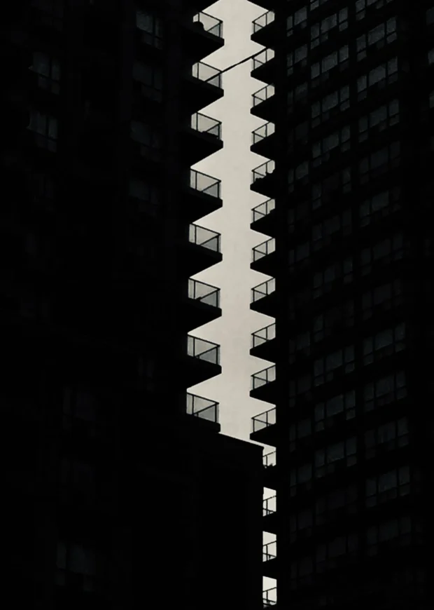 A dark tower with a zigzag of lit balconies.