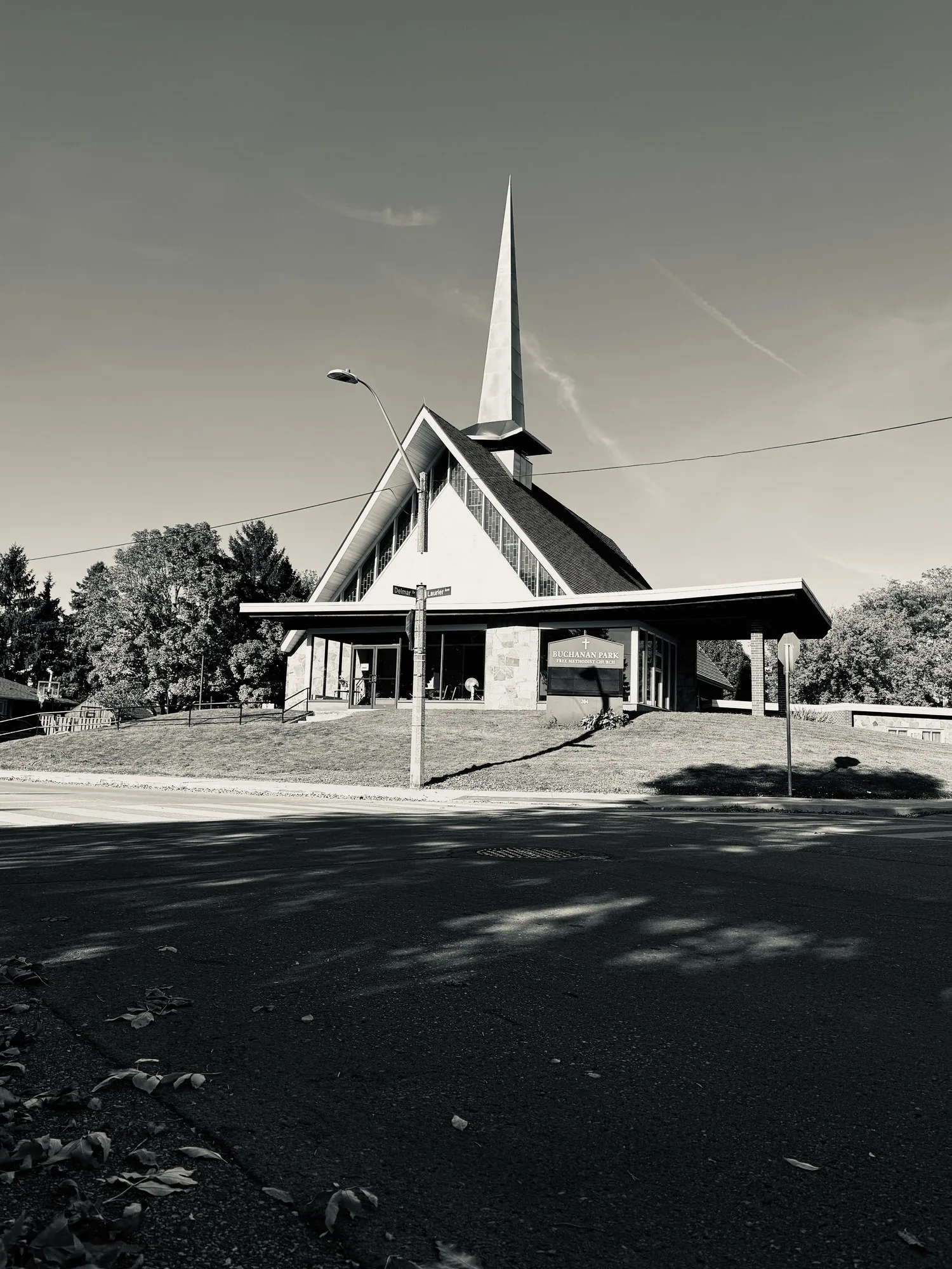 An A-frame church and spire against a dark sky, black and white.
