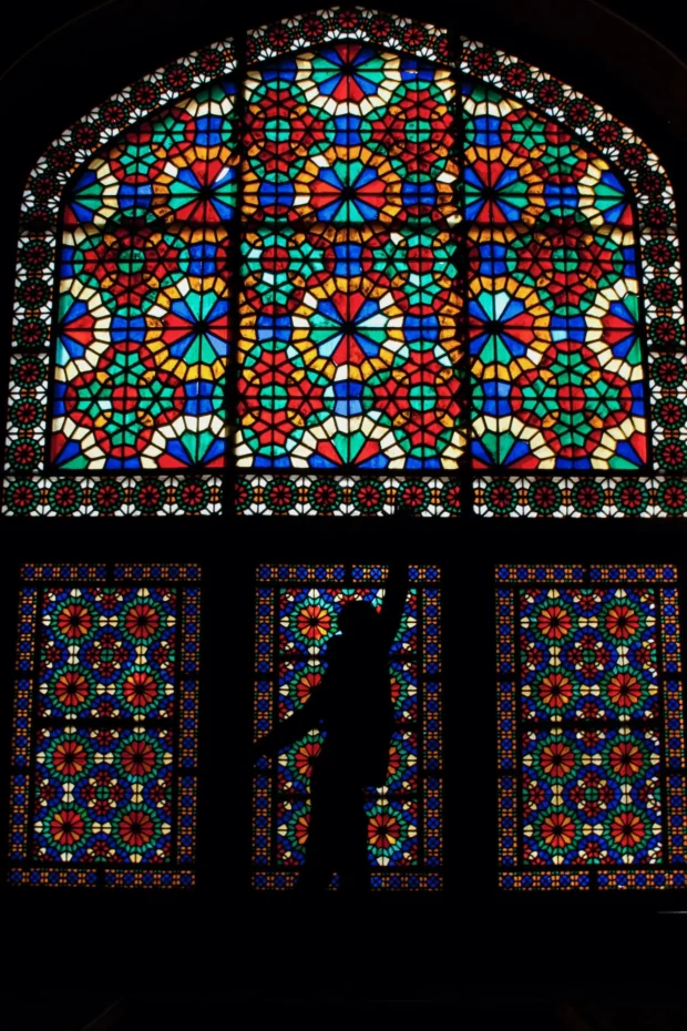 Stained glass, with a figure silhouetted against it.