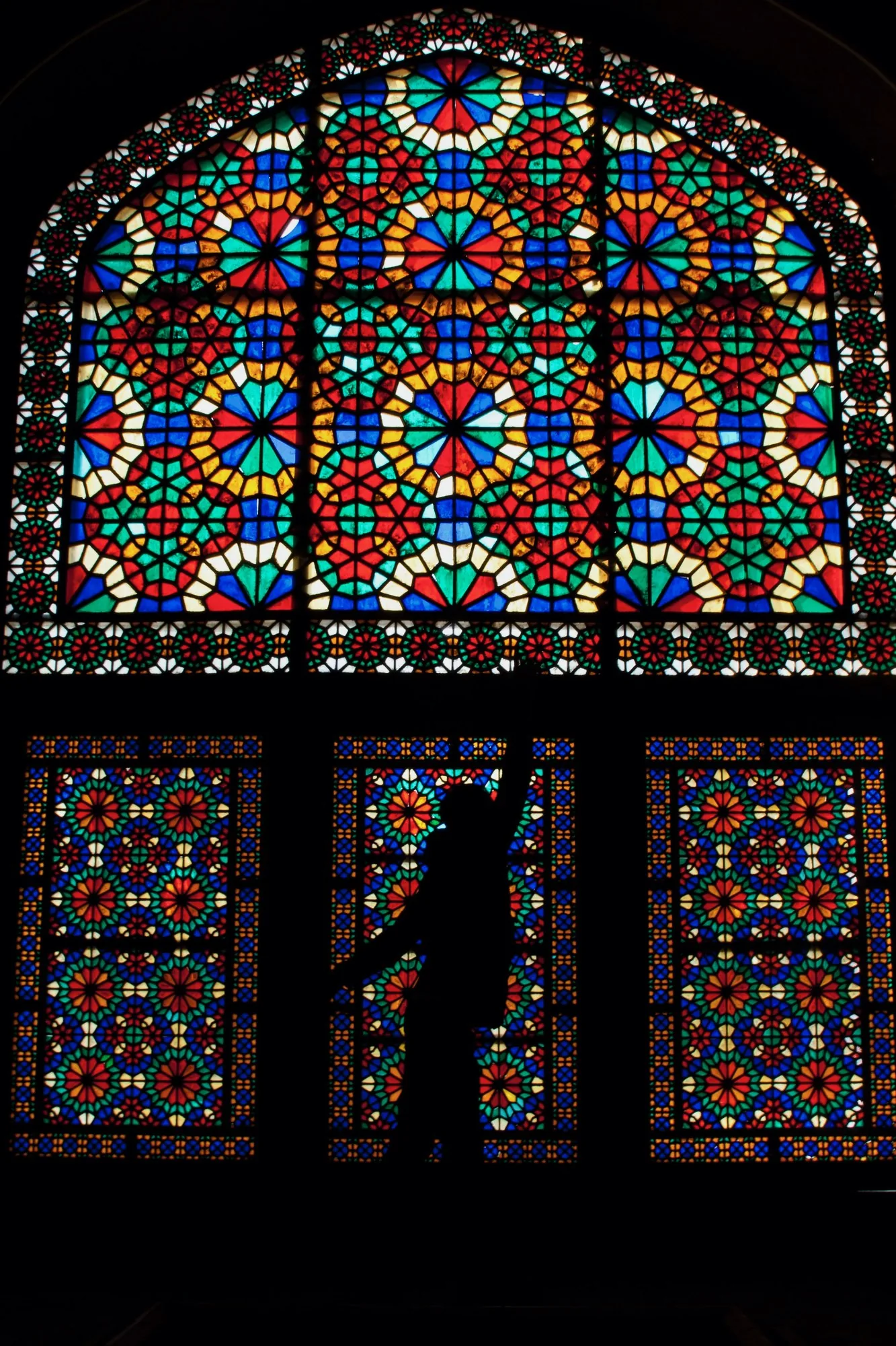 Stained glass, with a figure silhouetted against it.