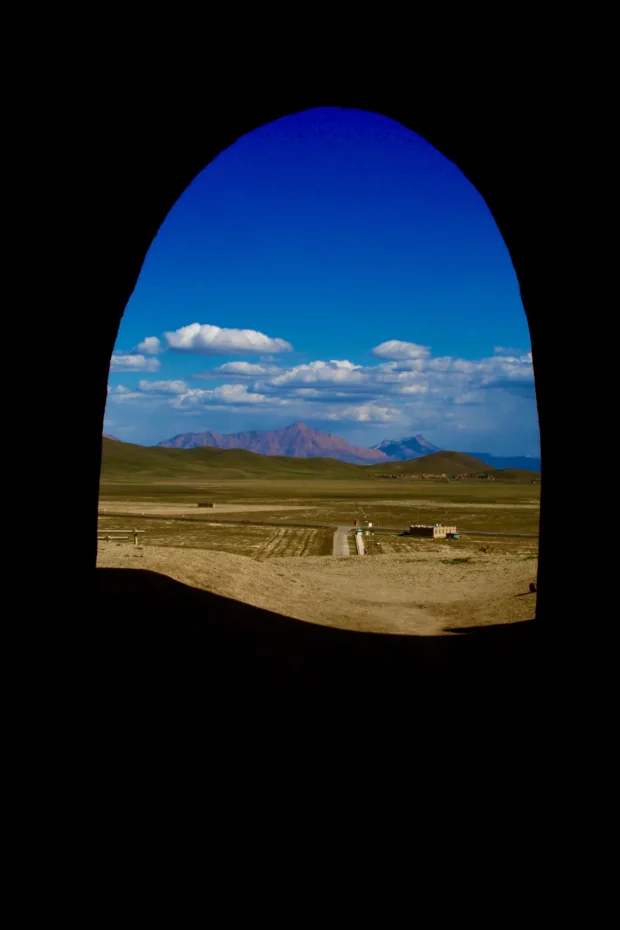 Desert and sky seen through a dark cave mouth, the opening a perfect arch.