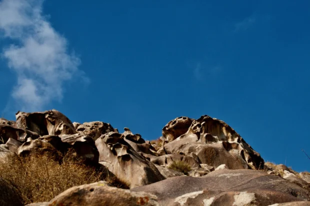 Honeycombed rock heads against blue.