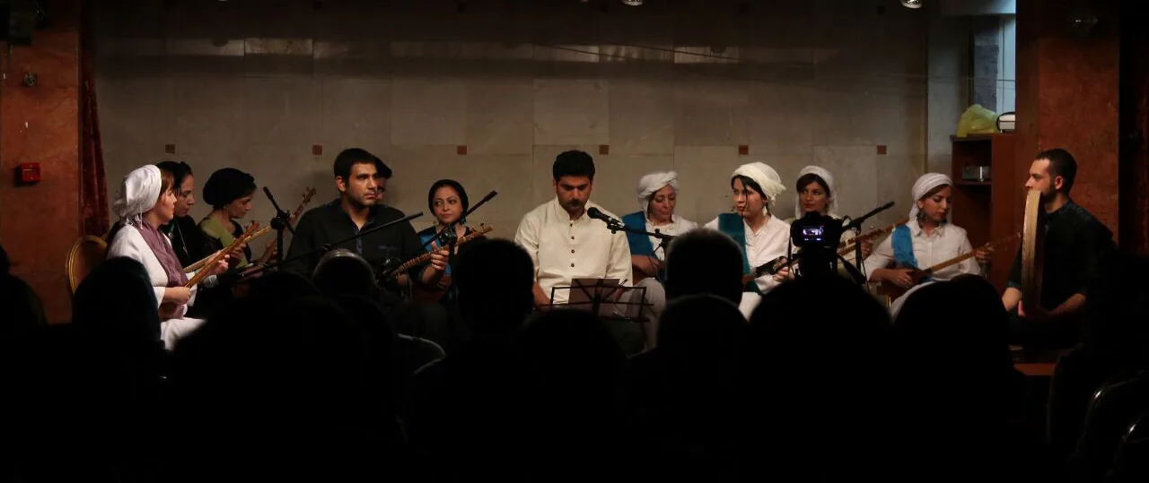 An ensemble on stage, the audience silhouetted in front.