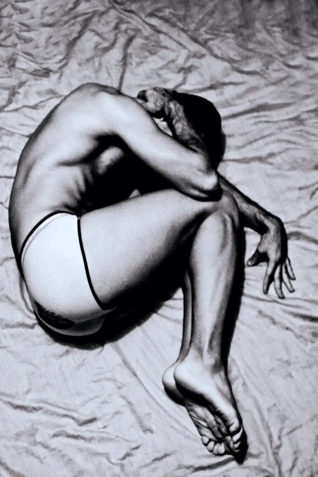 Curled on a sheet, seen from above, black and white.