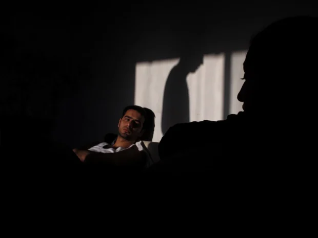 A figure lying in window light with a silhouetted head in the foreground.