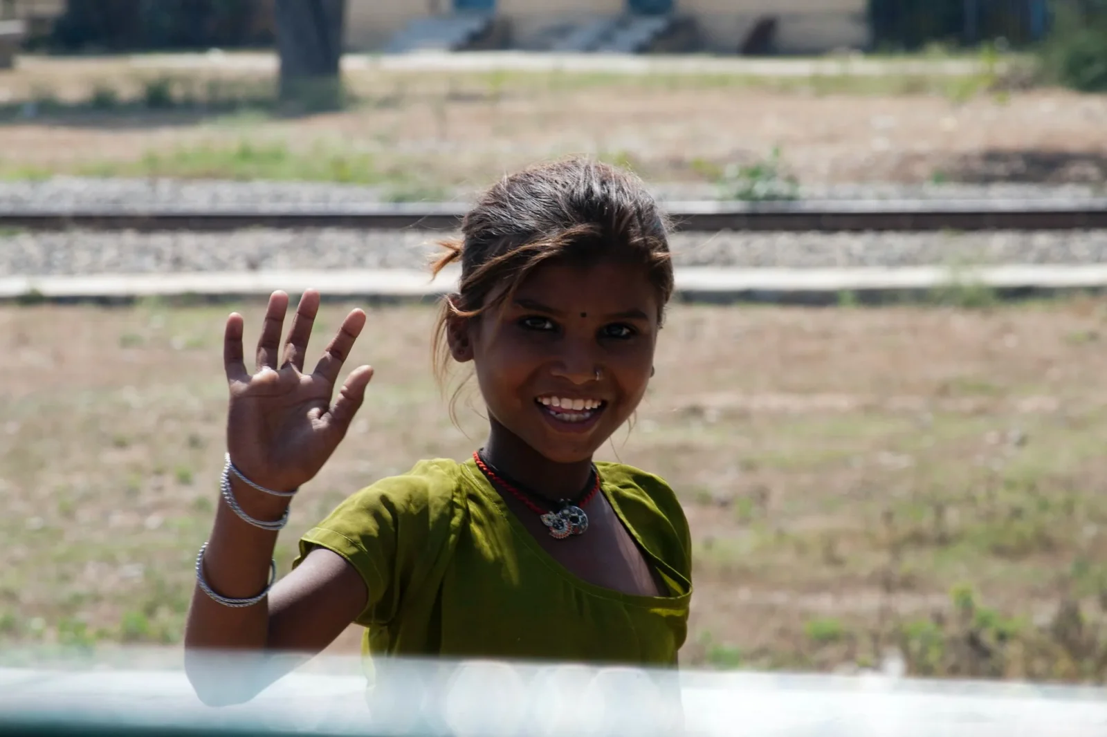 A girl waving over a sill, laughing.