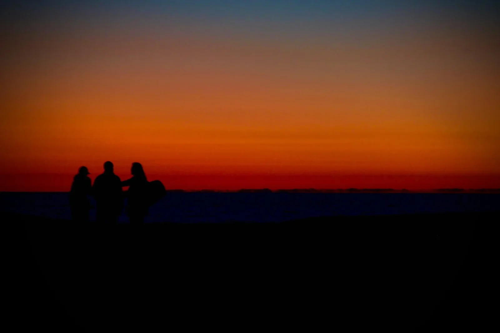 Two figures on a ridge against a red-to-blue gradient.