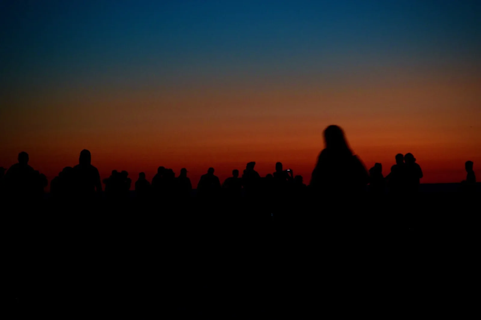 A row of people black against an orange band.